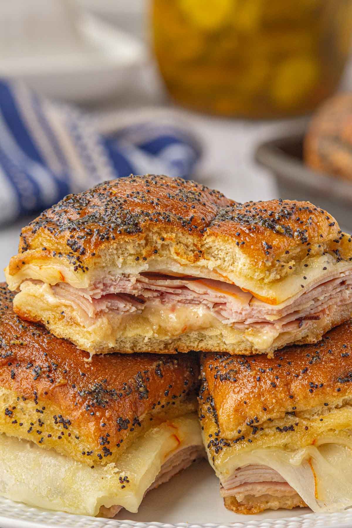 A stack of hot ham and cheese sliders on a party table.