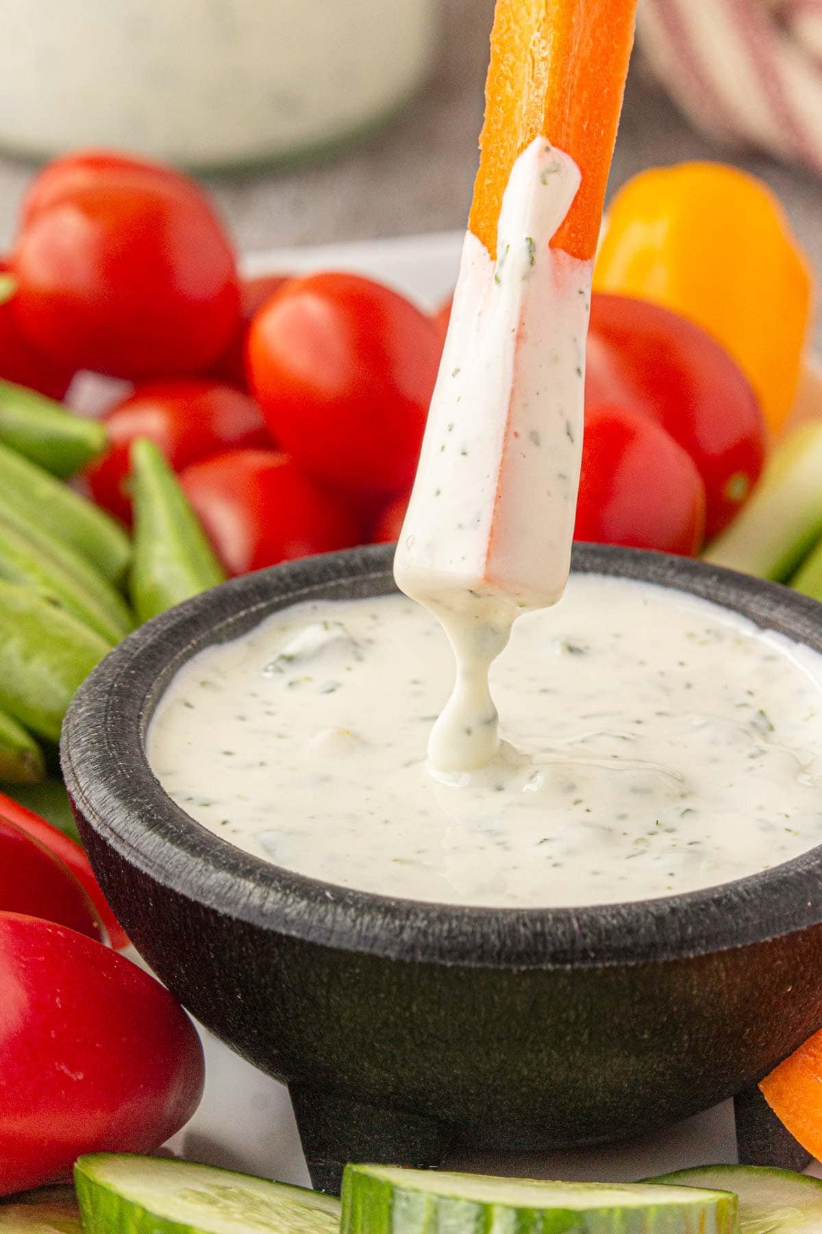 A carrot stick being dipped in homemade jalapeno ranch dip.