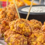 Closeup of pimento cheese sausage balls with a dip in the background.