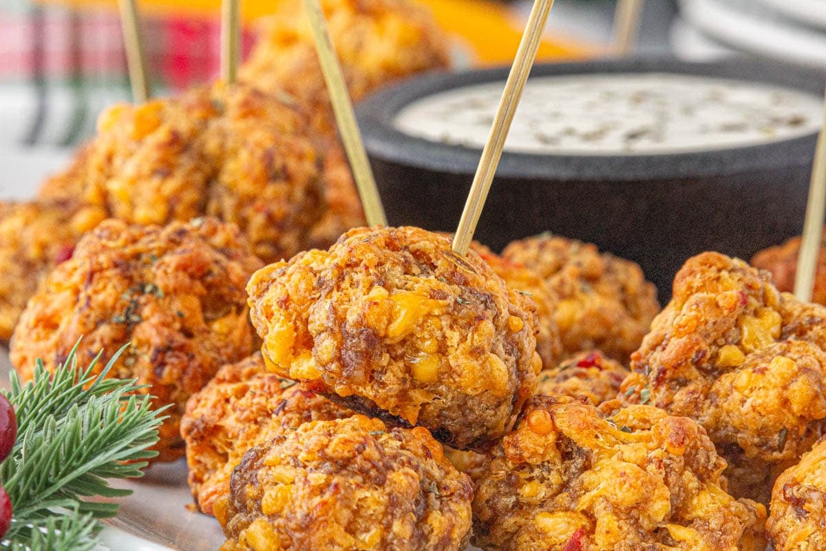Closeup of pimento cheese sausage balls with a dip in the background.