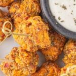 Pimento cheese sausage ball appetizers on a serving dish with text overlay for Pinterest.