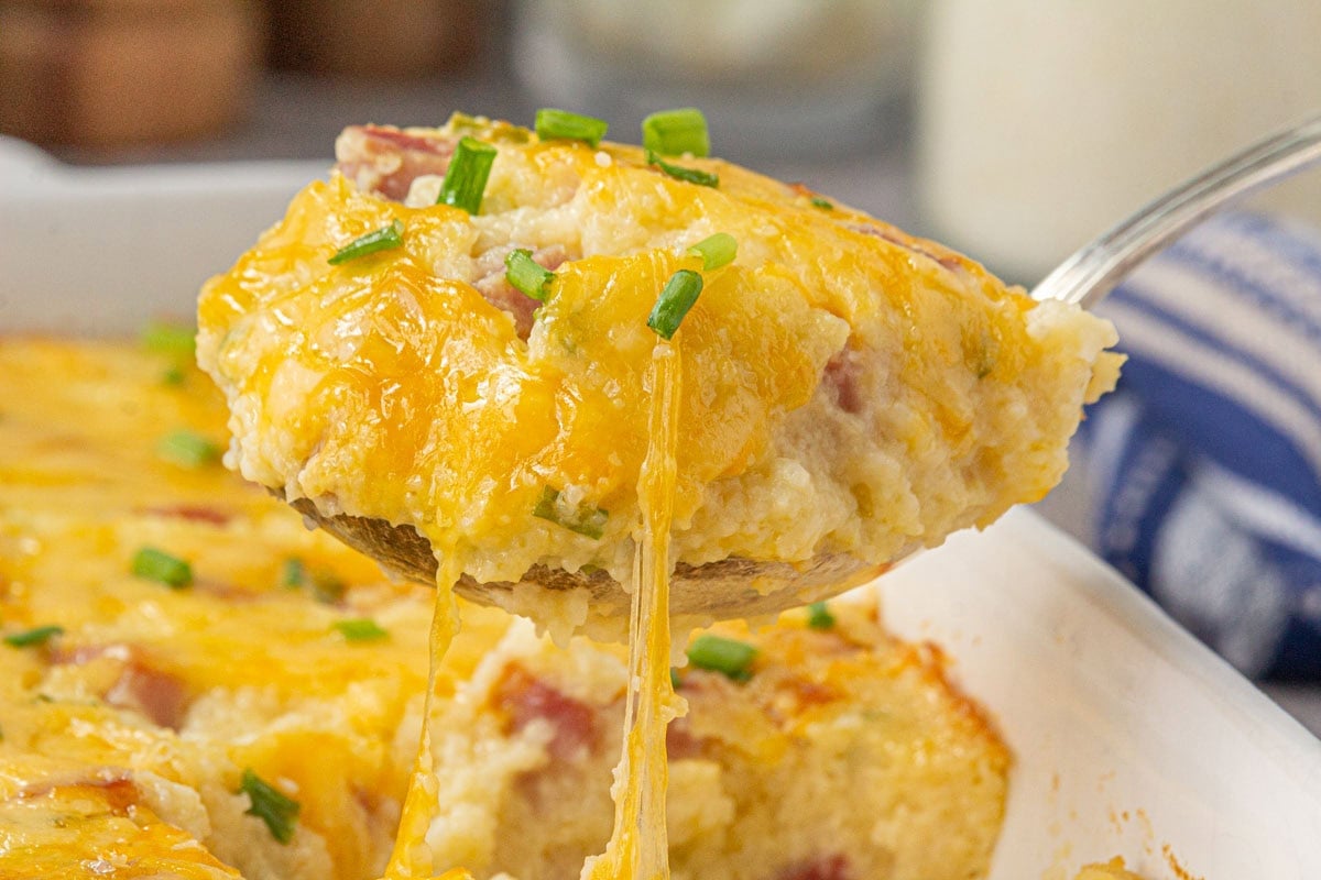 A closeup of ham and cheese grits breakfast casserole being served.