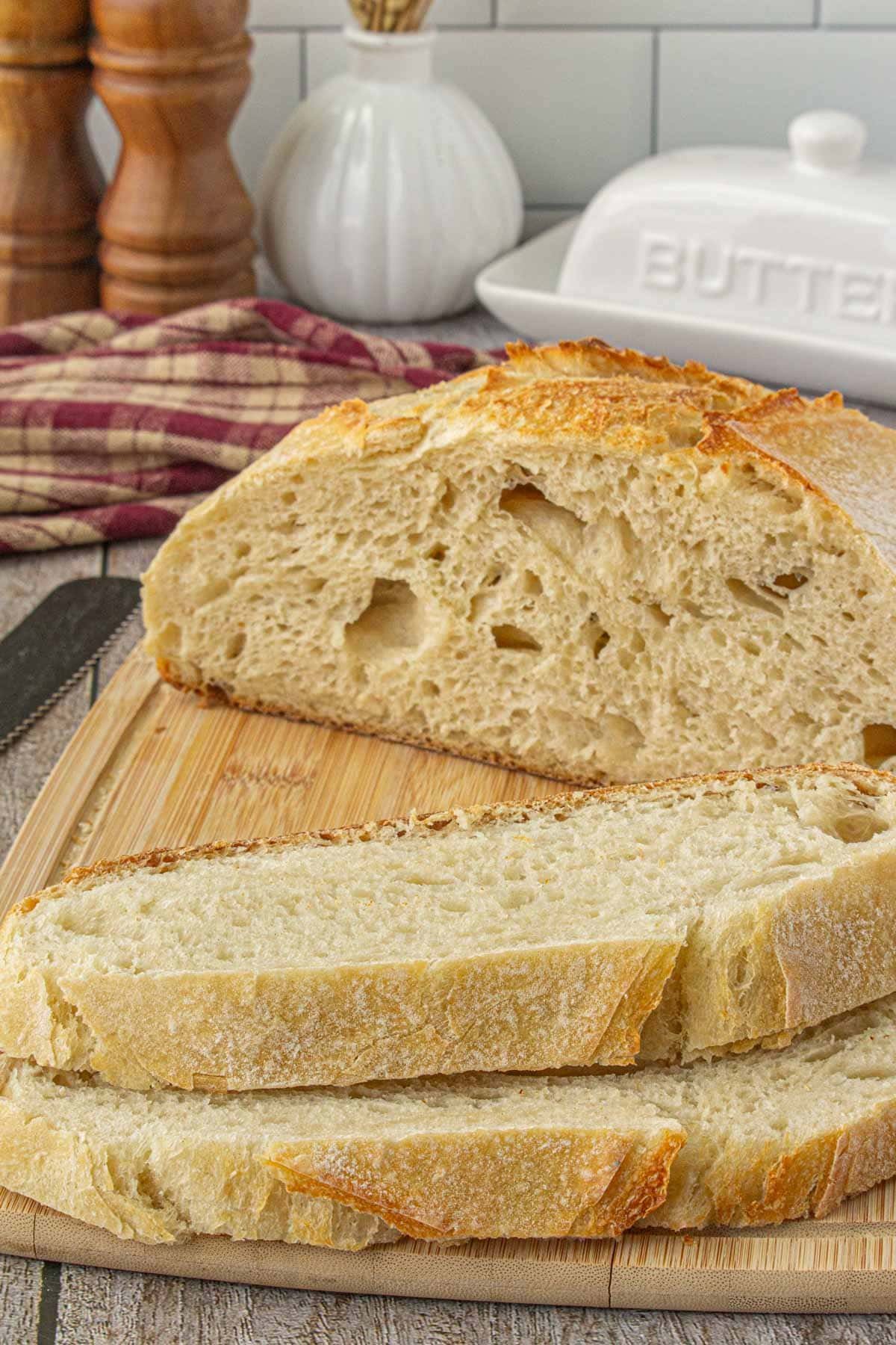 A loaf of artisan sourdough bread that has been sliced on a cutting board.