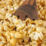 A wooden spoon in a batch of caramel popcorn.