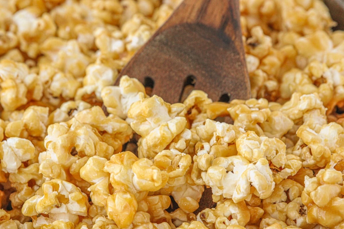 A wooden spoon in a batch of caramel popcorn.