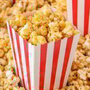 Overhead view of homemade caramel popcorn in a red and white striped box.