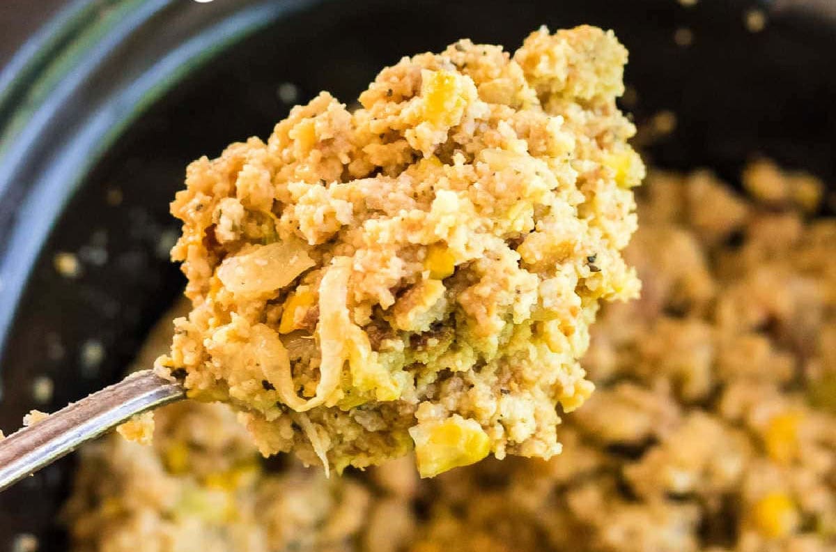 Spoonful of fluffy crockpot cornbread dressing with onion and creamed corn.