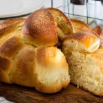 Freshly baked Pan de Muerto loaf cut open to show the soft, fluffy crumb inside, topped with sugar and decorated with bone-shaped dough pieces.