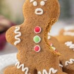 Christmas gingerbread cut out cookies Pinterest pin image featuring a bitten gingerbread man decorated with white icing and red and green buttons, with text overlay reading “Gingerbread Cut Out Cookies – Gingerbread Men with Attitude.
