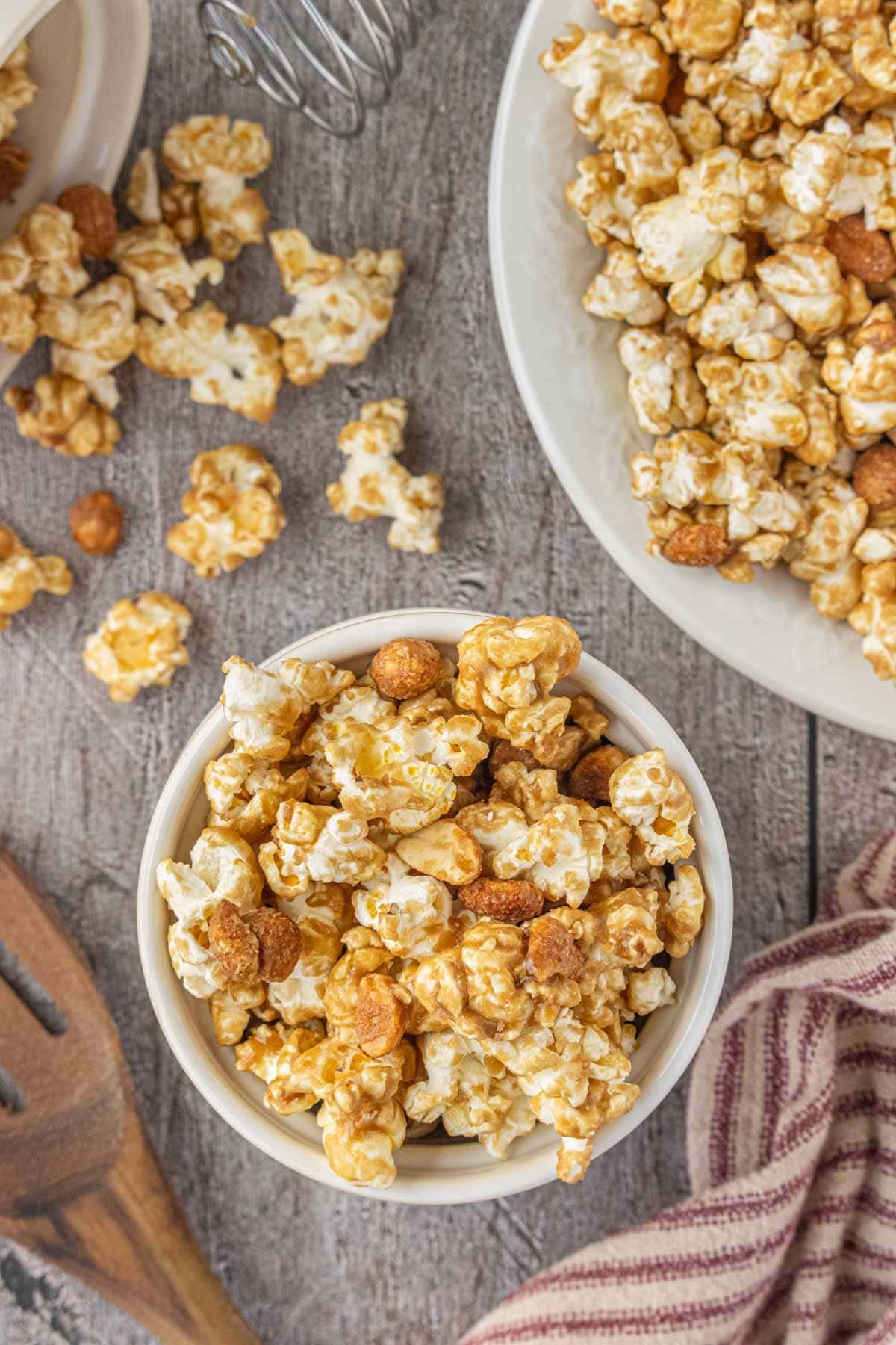 Overhead view of homemade Cracker Jack popcorn with peanuts and a brown sugar molasses glaze in a white bowl.