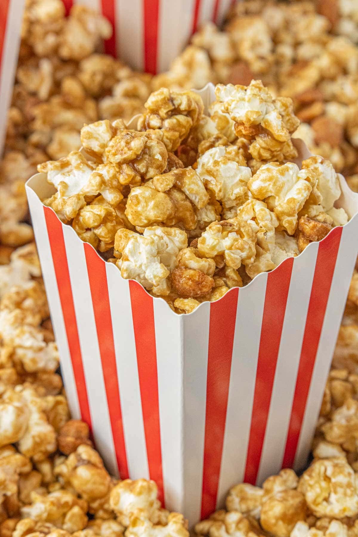 Copycat cracker jack popcorn in a red and white striped box overflowing with crisp, glazed popcorn.