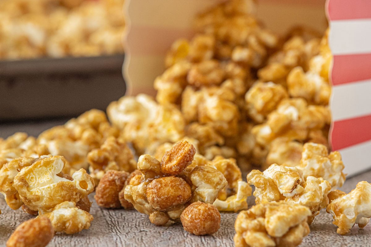 A red and white striped box tipped over with Cracker Jack popcorn spilling out of it.