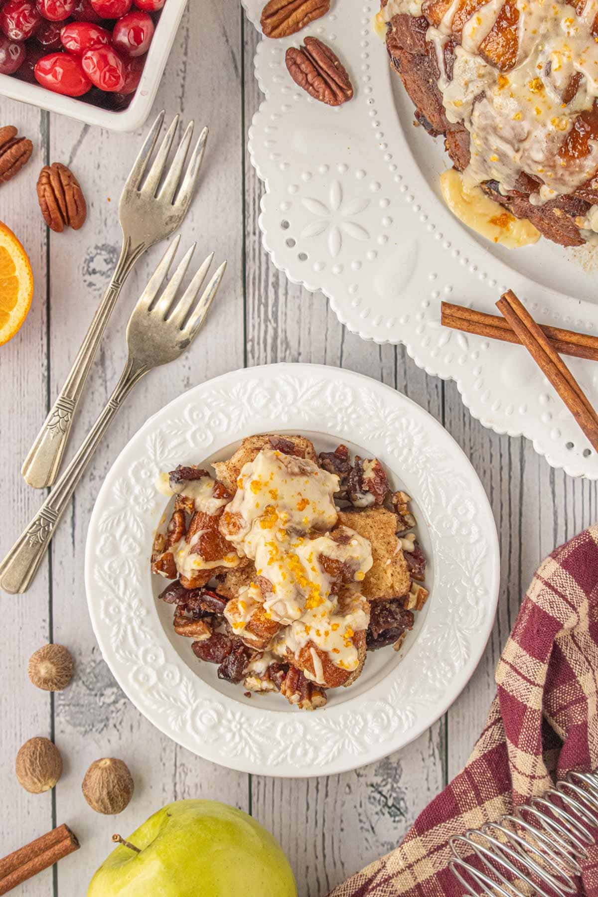 Festive slow-cooker monkey bread served on white plates with cinnamon, oranges, and pecans - cozy holiday brunch idea for Christmas morning.