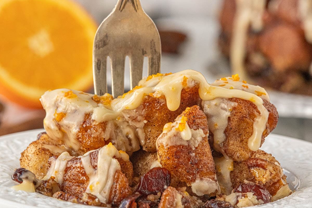 Gooey crockpot monkey bread drizzled with orange glaze and topped with pecans - warm pull-apart bread perfect for Christmas breakfast.
