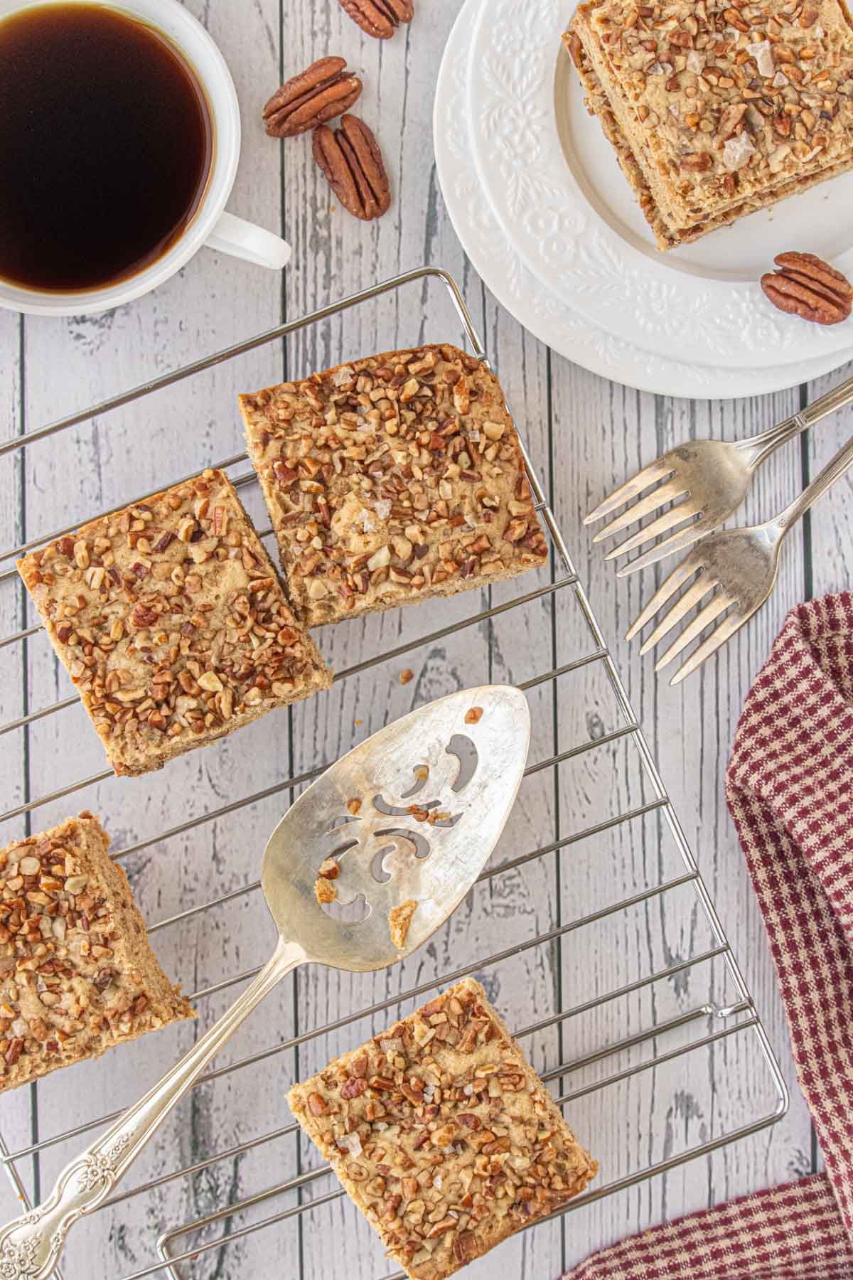 Two thick maple-pecan blondies perched on a spatula-golden, buttery, and piled high with crunchy pecans, just begging for a cup of coffee.