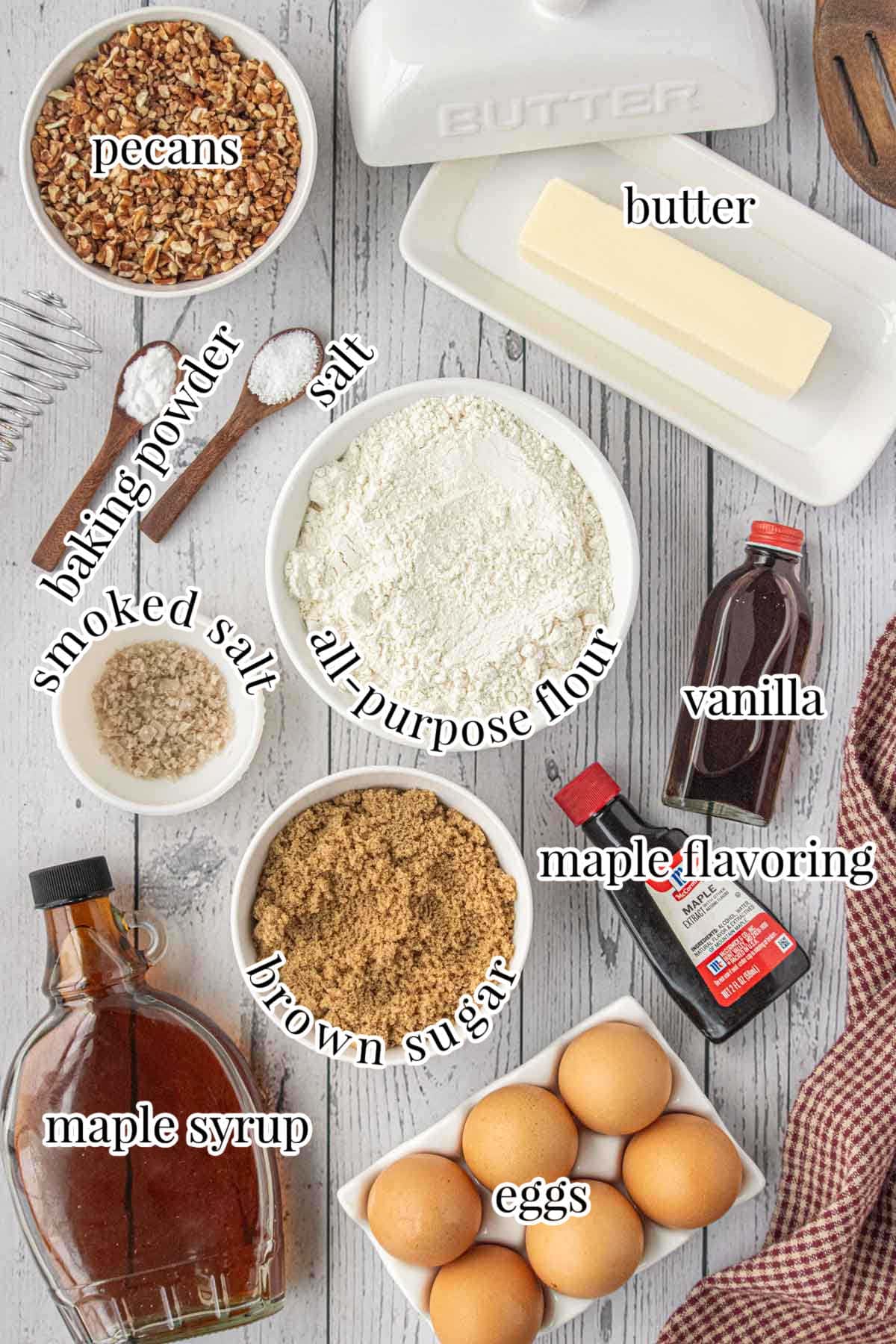 Ingredients for homemade maple pecan blondies-brown sugar, maple syrup, butter, flour, pecans, vanilla, and eggs arranged on a rustic gray table.