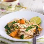 Vertical Pinterest image with text overlay reading “Chicken & Sweet Potato Stew – Light & easy on the digestive system for chemo patients.” The image shows a bowl of shredded chicken stew with sweet potatoes, spinach, and lime on a rustic white table, styled with a green-striped napkin and vintage teacup.
