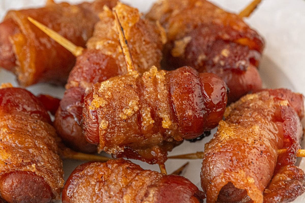 Baked maple chipotle bacon wrapped little smokies on a plate, showing browned bacon and caramelized brown sugar glaze.