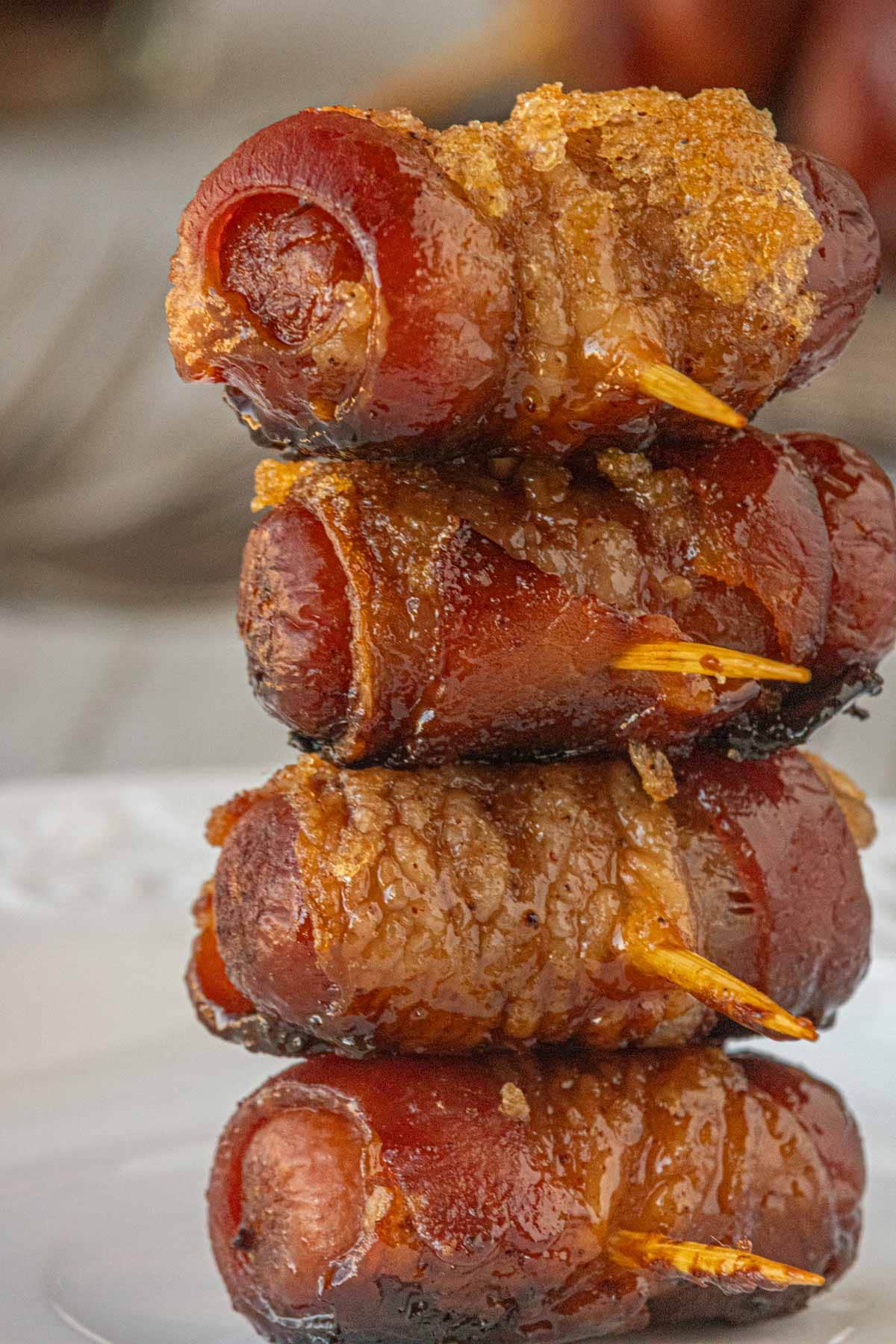 Stacked maple chipotle bacon wrapped little smokies secured with toothpicks, showing crisp bacon and sticky maple chipotle coating.