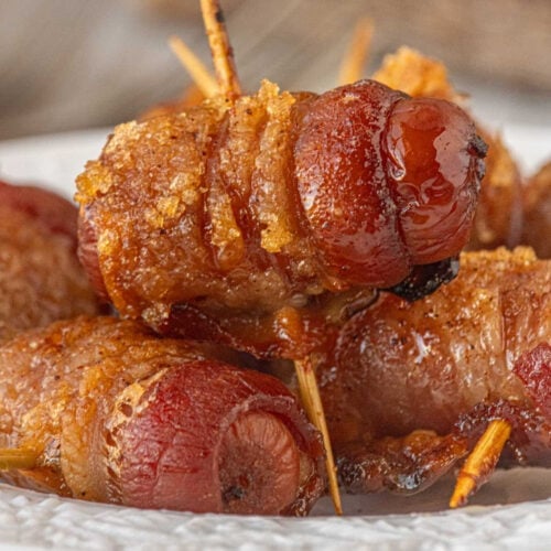 Close-up of baked maple chipotle bacon wrapped little smokies with caramelized bacon and glossy sweet and spicy glaze.