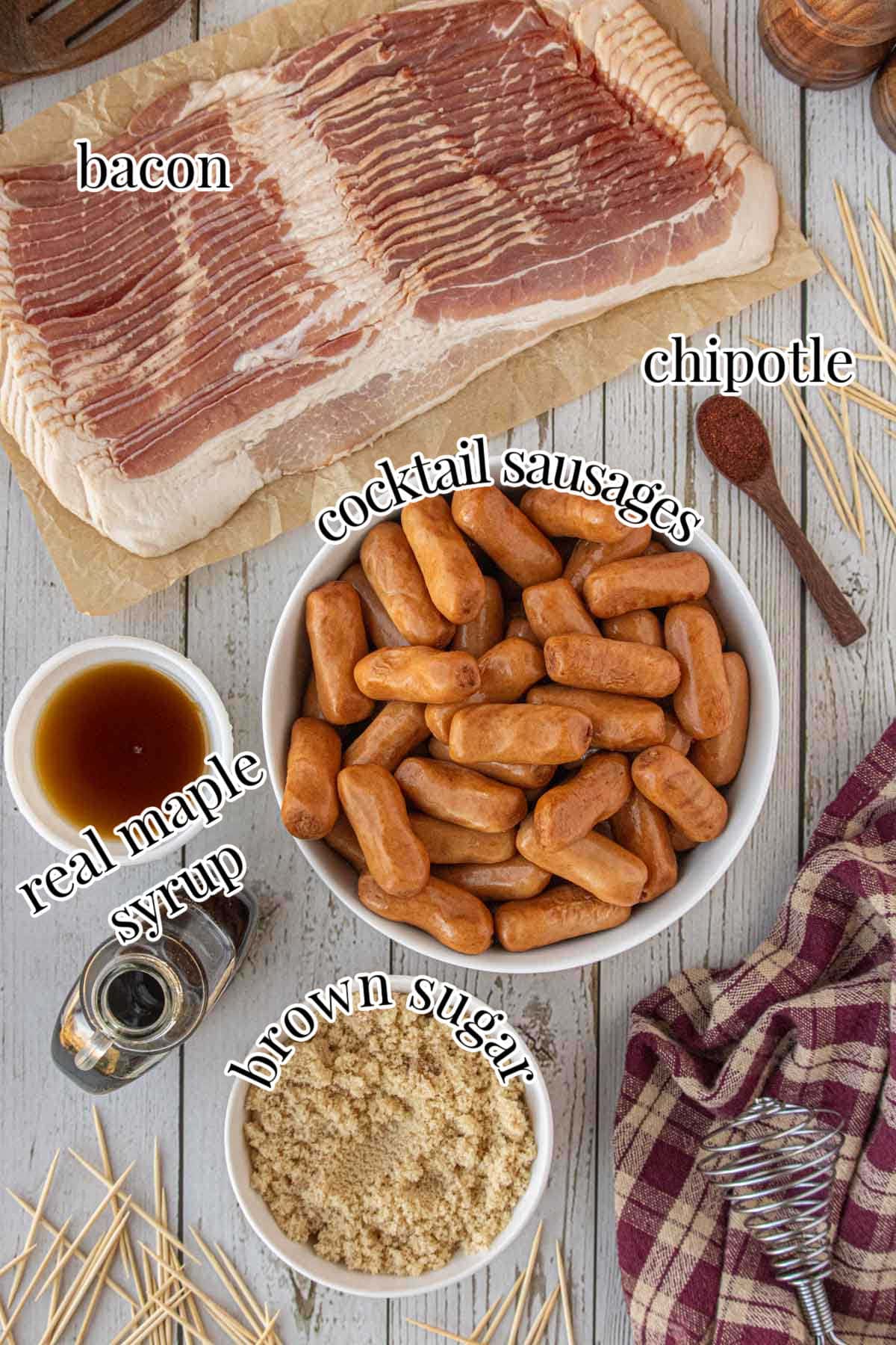 Ingredients for maple chipotle bacon wrapped little smokies including bacon, cocktail sausages, brown sugar, real maple syrup, and chipotle seasoning arranged on a work surface.
