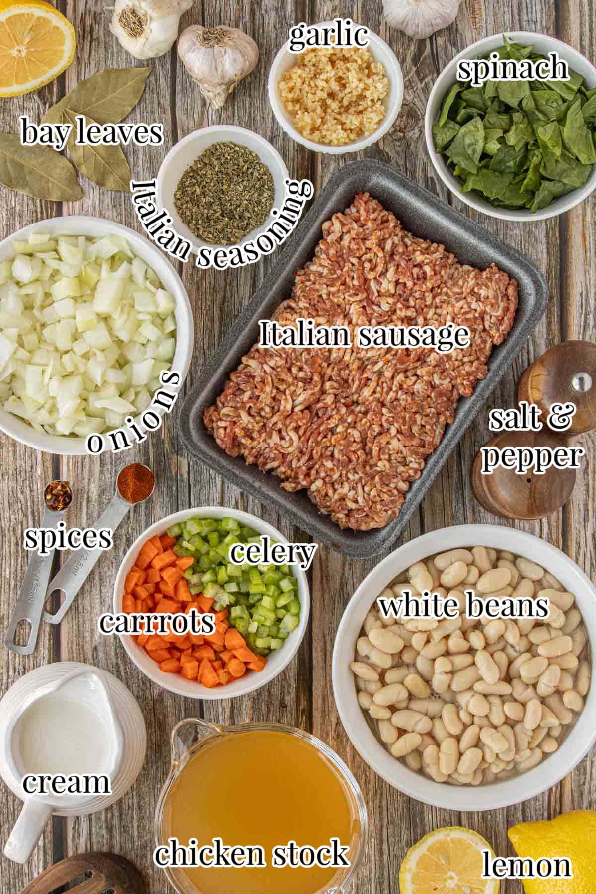 Overhead image of labeled ingredients for sausage and white bean soup, including Italian sausage, white beans, onion, garlic, carrots, celery, spinach, Italian seasoning, bay leaves, chicken stock, heavy cream, lemon, and salt and pepper, photographed by Kim Ledet for Marye Audet at Restless Chipotle.