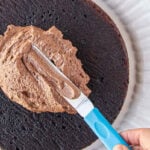 Frosting a cake with the chocolate fudge frosting and an offset spatula.