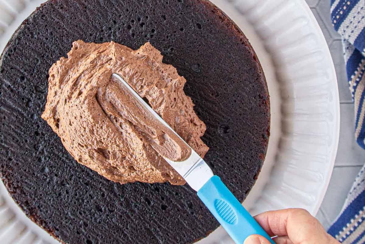 Frosting a cake with the chocolate fudge frosting and an offset spatula.