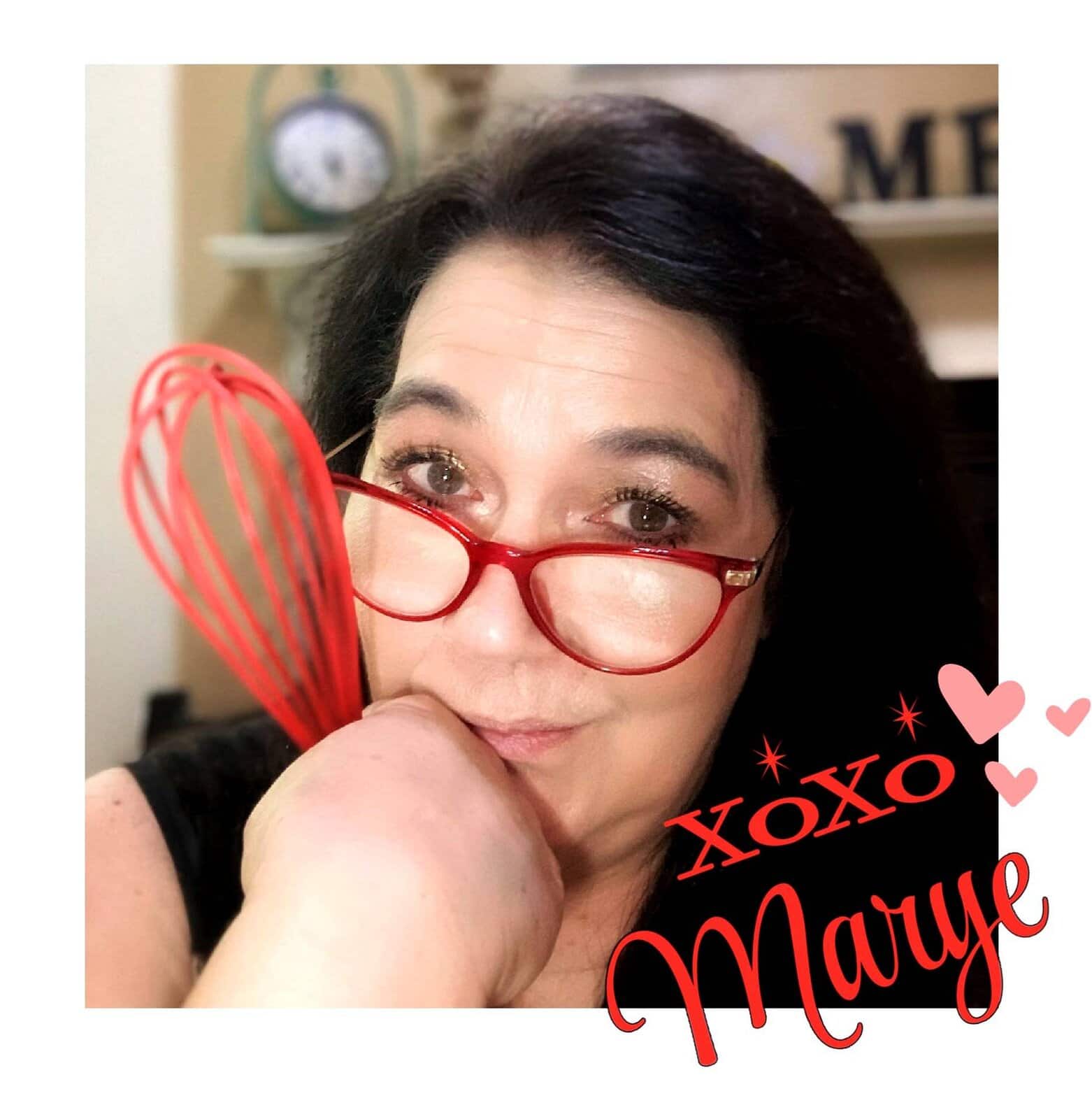 Marye Audet wearing red glasses and holding a red whisk, smiling, with the text “XOXO Marye.”