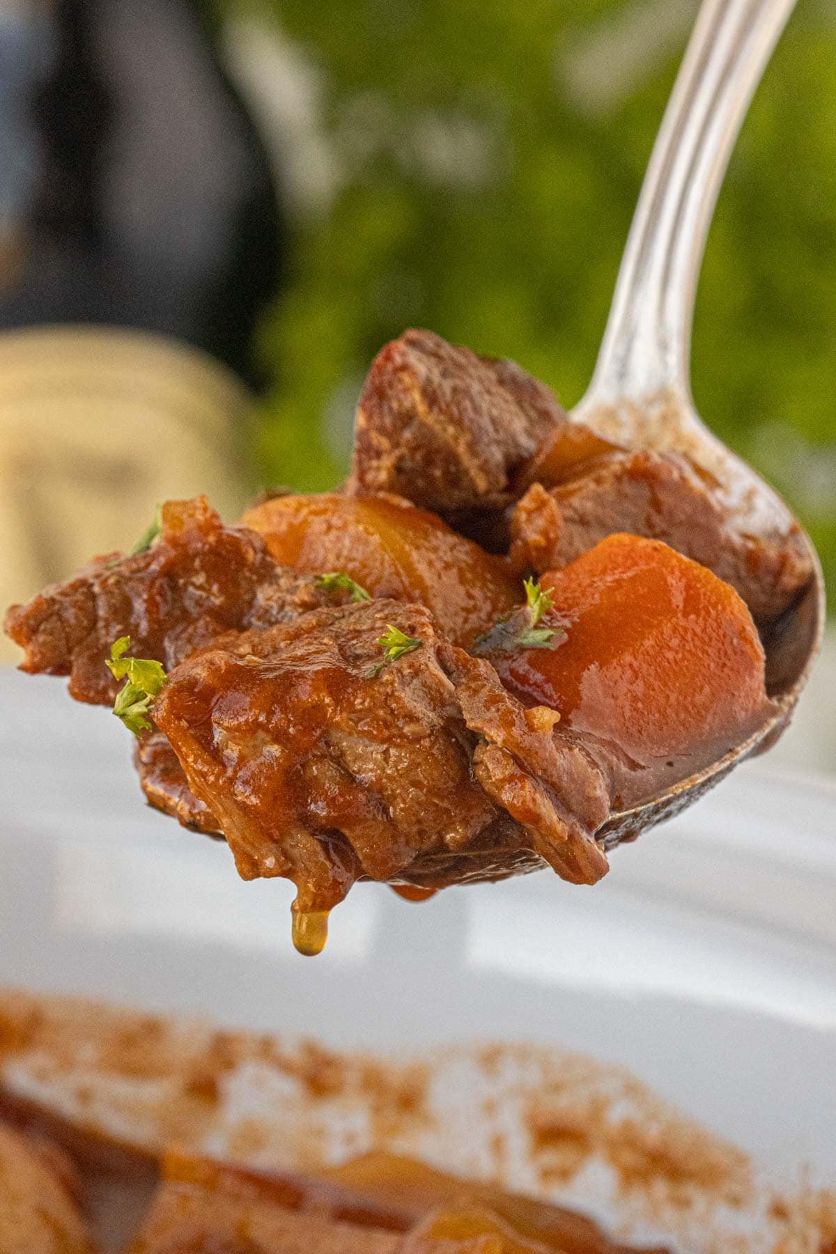 Spoonful of Guinness beef stew lifted from slow cooker showing tender beef and glossy sauce