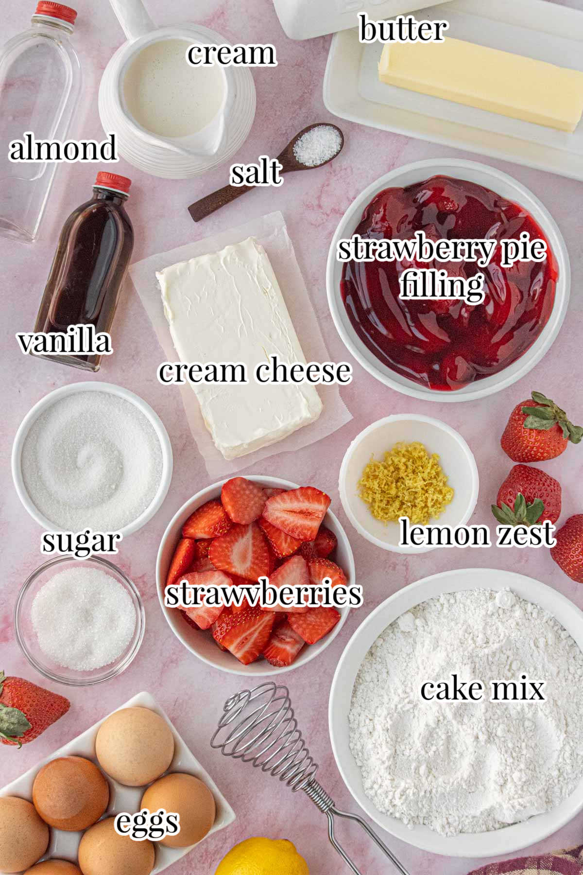 Ingredients for strawberry cream cheese dump cake including cake mix, cream cheese, strawberry pie filling, fresh strawberries, butter, eggs, sugar, cream, vanilla, salt, and lemon zest arranged on a pink surface