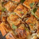 Overhead view of sliced sourdough pull-apart bread filled with bacon, ranch butter, and shredded cheese before baking on a wooden board. Title text for pinterest says Bacon Ranch Pull Apart Bread - Pull Apart. Lose Control.