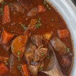 Irish Guinness beef stew simmered until tender with carrots, potatoes, and onions with title text for Pinterest.