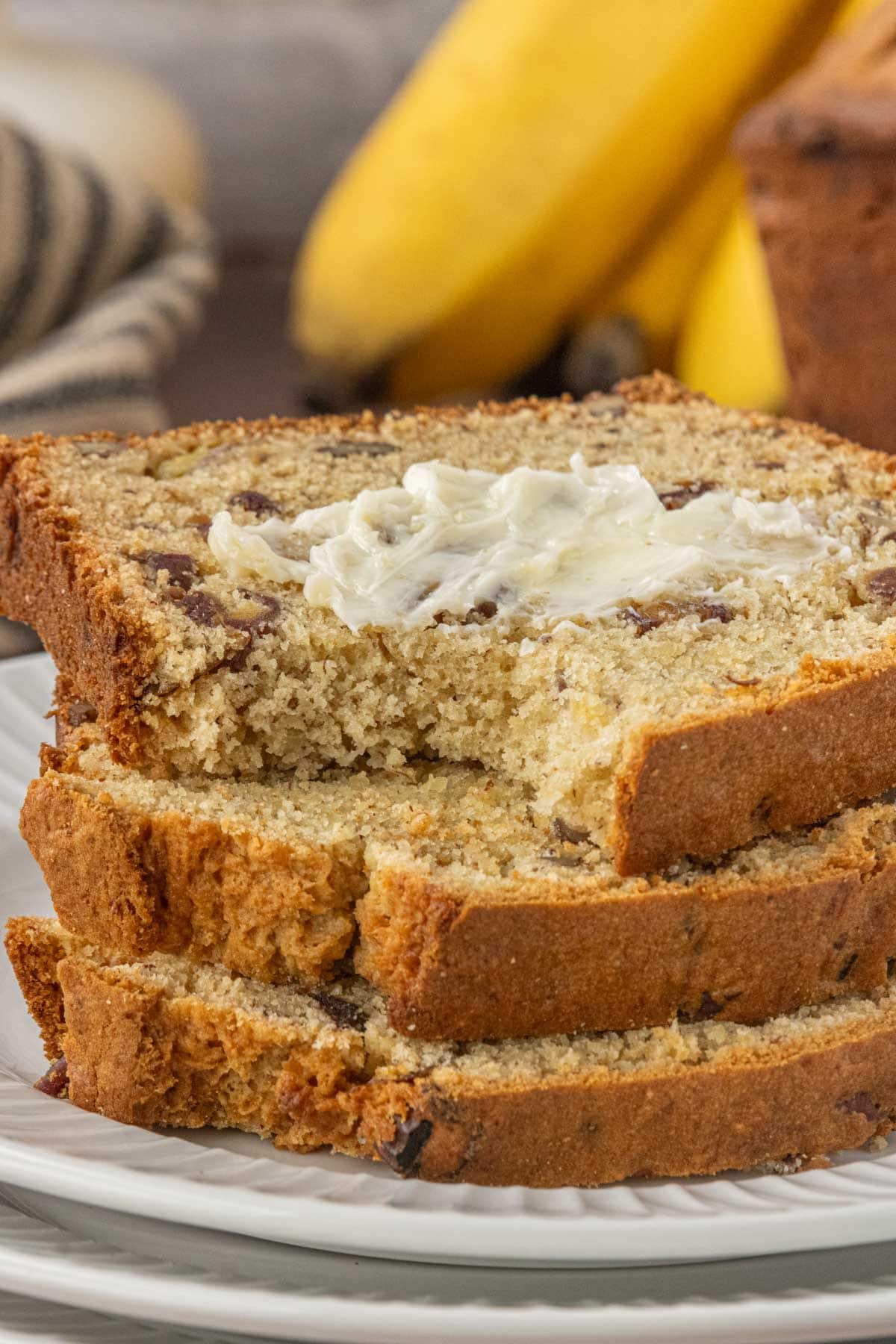 Slices of banana date bread stacked with butter melting into the warm crumb.
