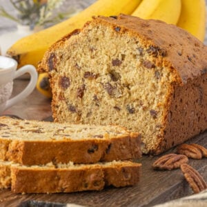 Sliced banana date bread on a wooden board showing a tender crumb with chopped dates and pecans.
