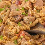 Close up Cajun chicken and sausage pasta being stirred showing creamy Cajun sauce and rotini pasta