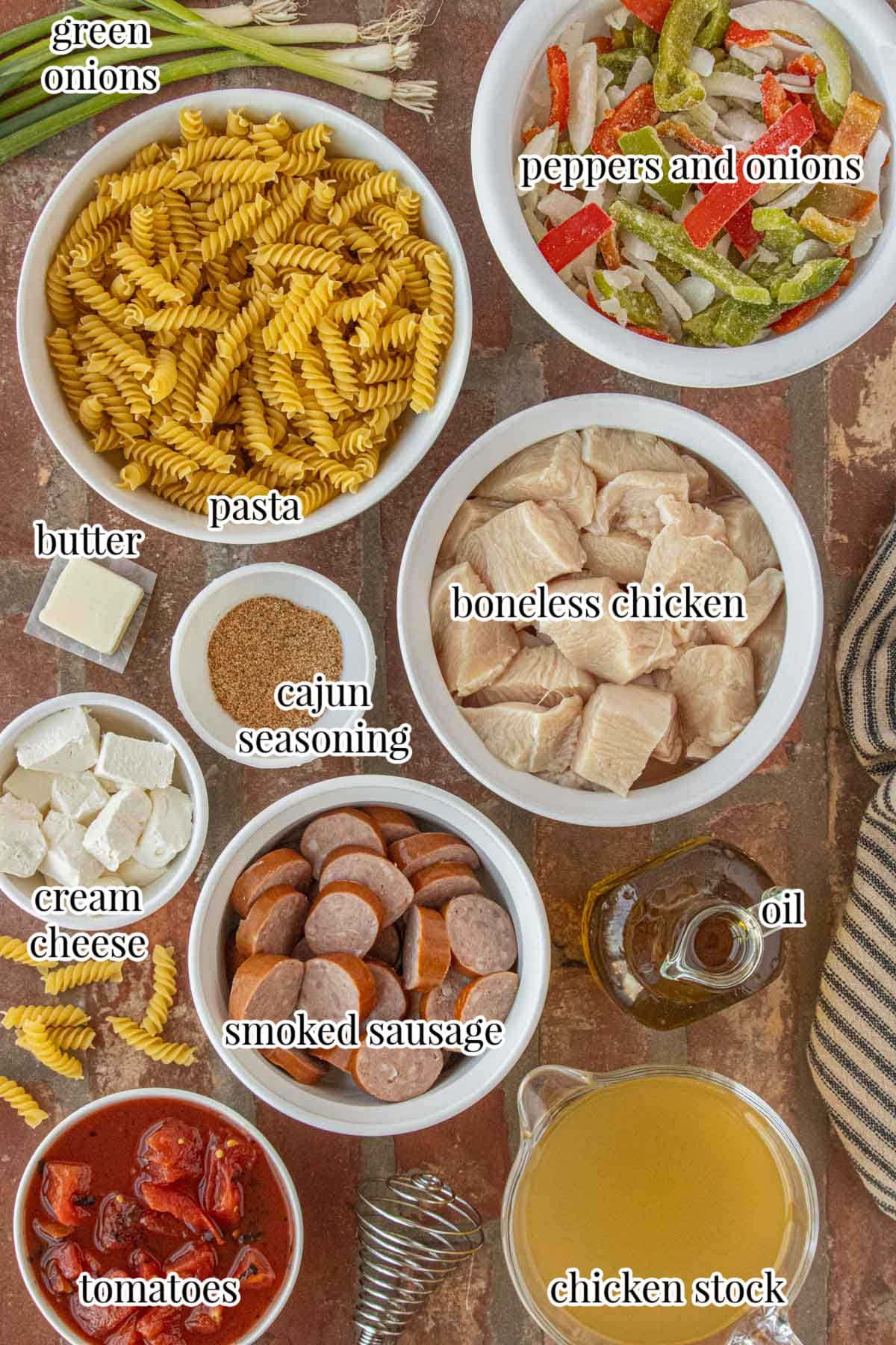 Ingredients for Cajun chicken and sausage pasta including chicken sausage pasta Cajun seasoning cream cheese and peppers