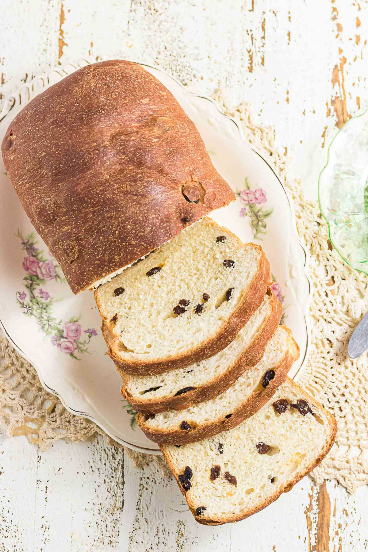 Homemade raisin bread loaf sliced on vintage floral plate with soft crumb and golden crust