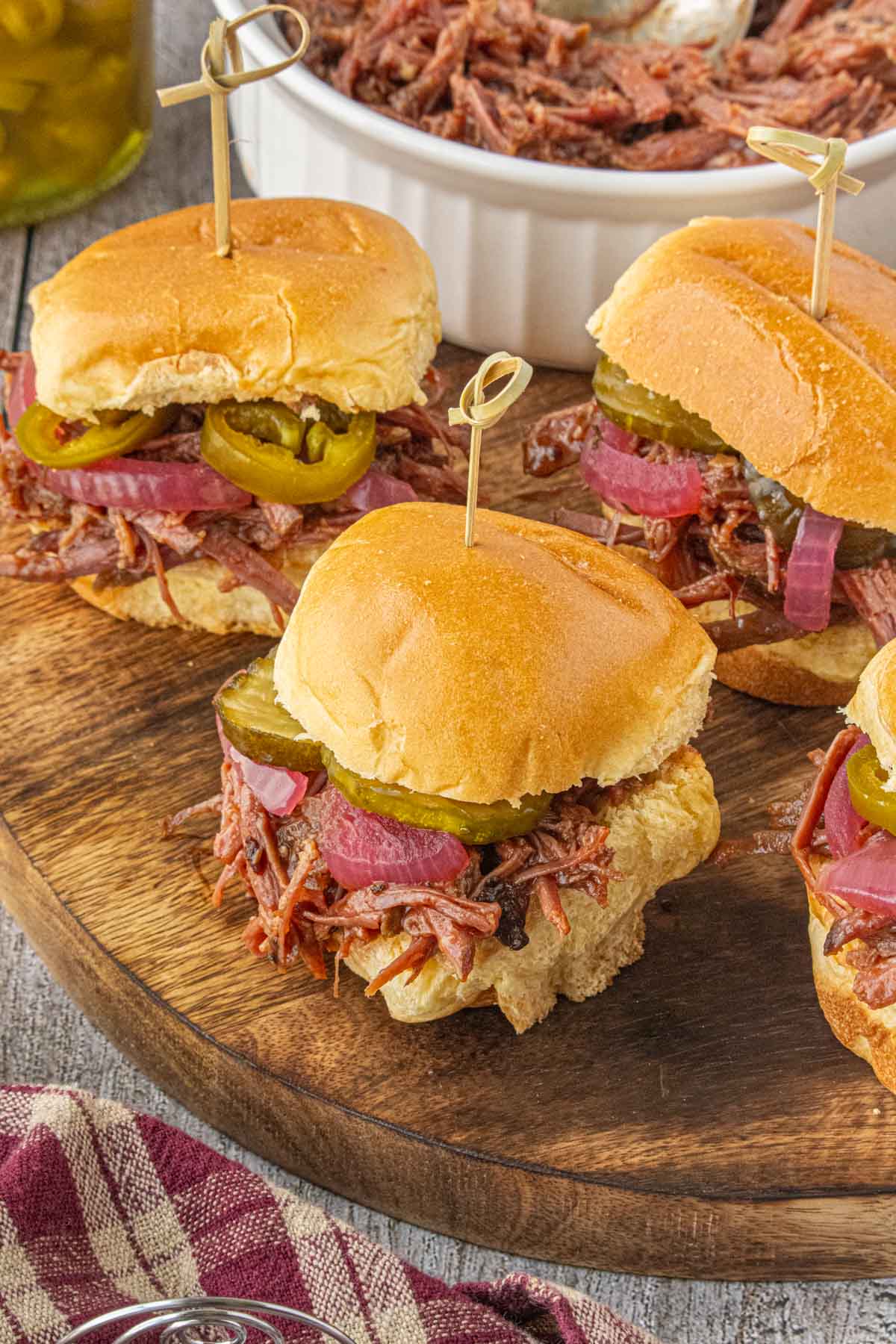 Tray of slow cooker brisket sliders with pickles and pickled onions served on soft slider buns.