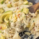 baked skillet enchiladas suizas topped with melted cheese and fresh avocado in cast iron pan