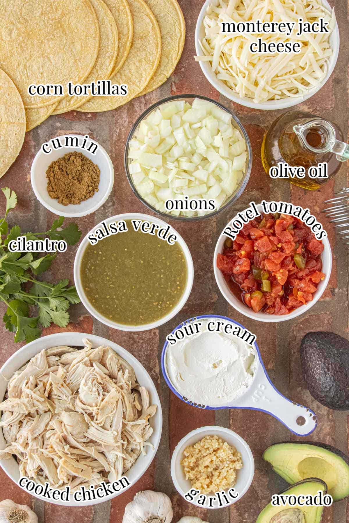 ingredients for enchiladas suizas including chicken, salsa verde, sour cream, cheese, tortillas, and avocado