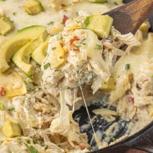 creamy chicken enchiladas suizas with gooey melted cheese being scooped from skillet