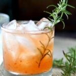 Spicy peach margarita with tequila, lime, and pepper jelly served over ice with a rosemary garnish.