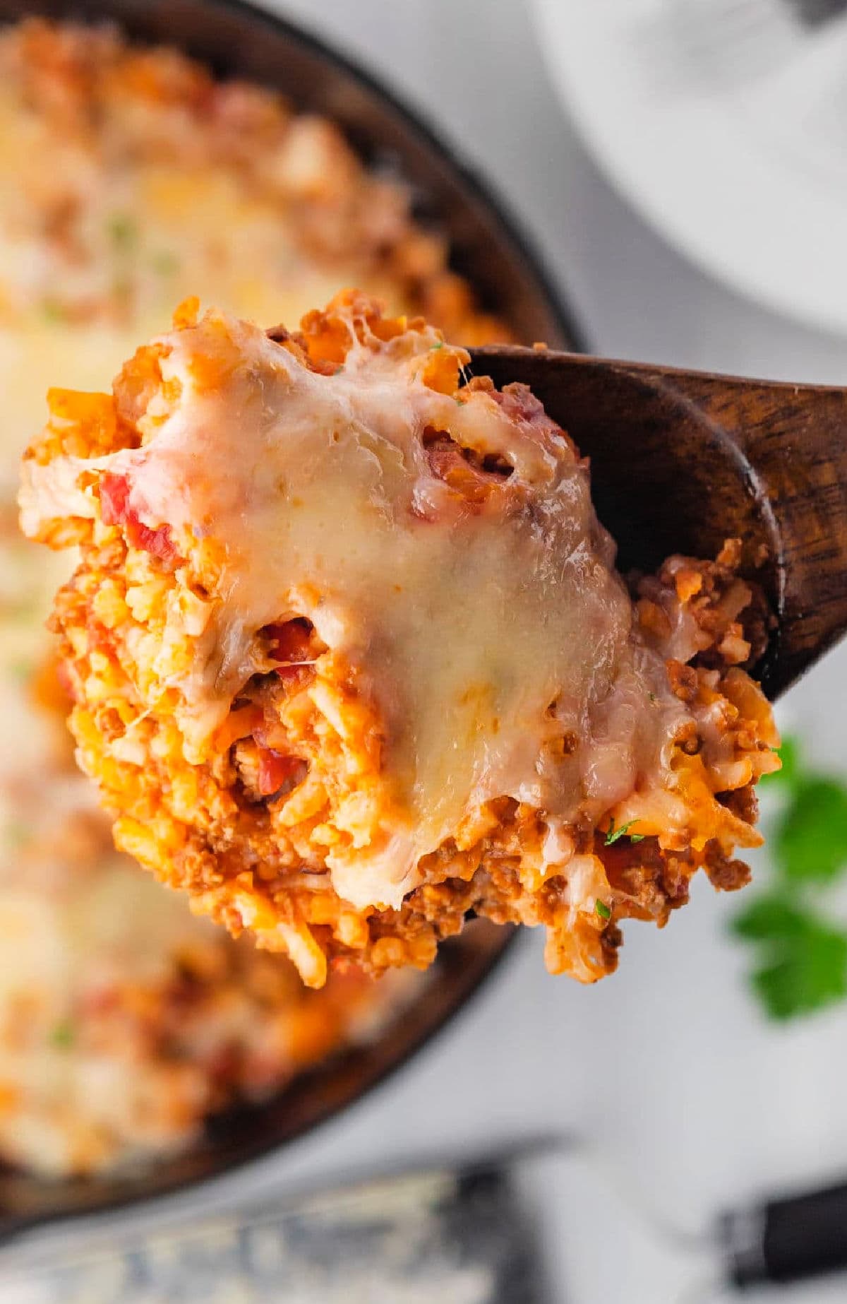 close up of cheesy stuffed pepper skillet casserole with ground beef, rice, and bell peppers on a spoon
