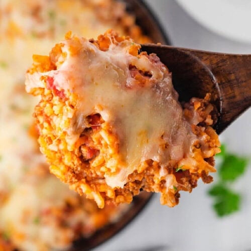 close up of stuffed pepper skillet casserole with instant rice, ground beef, and melted cheese on a wooden serving spoon