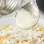 Creamy homemade 3 ingredient Alfredo sauce spooned over fettuccine pasta on a white plate