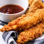 Copycat Popeye's Chicken tenders on a black and white napkin with text overlay for Pinterest