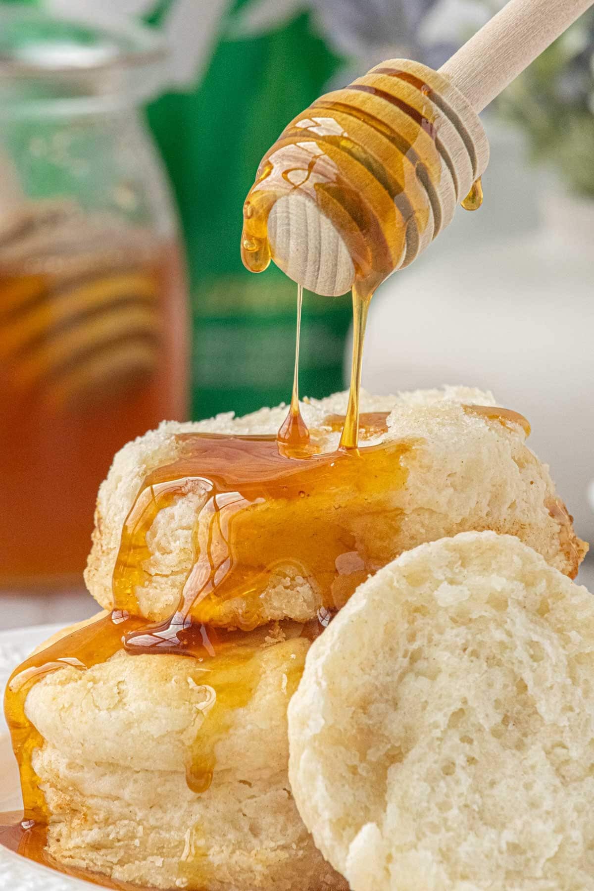 Honey drizzled over warm 3-ingredient biscuits with a wooden honey dipper
