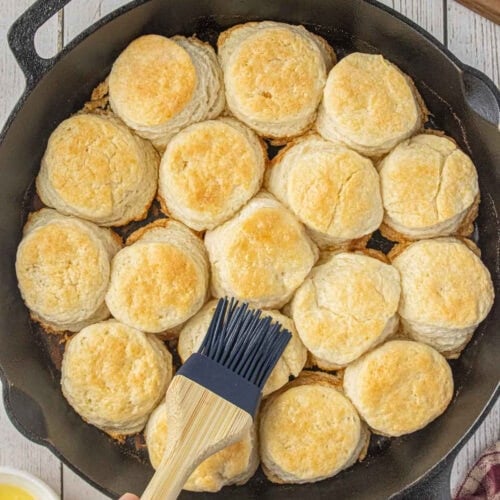 Golden 3-ingredient biscuits baked in a cast iron skillet with melted butter brushed on top
