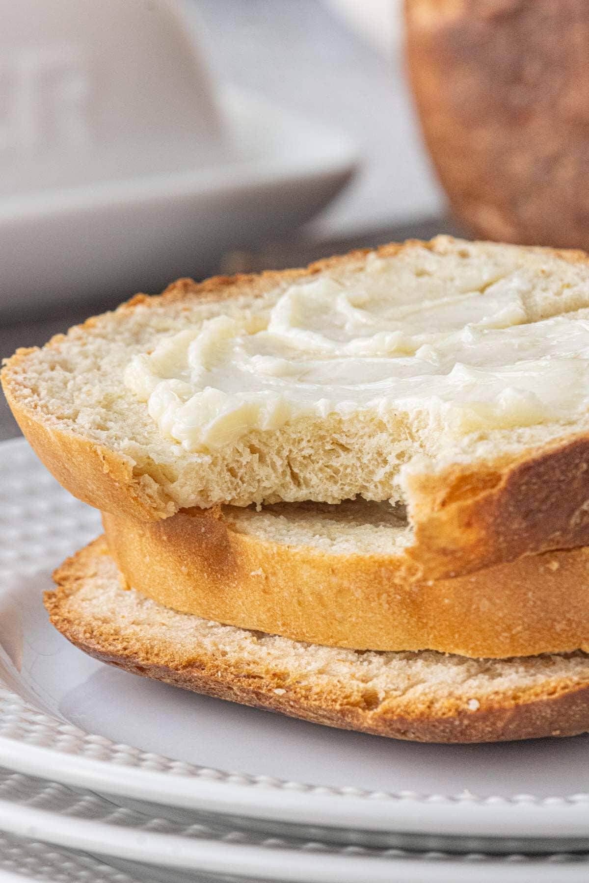 Close-up of a buttered slice of homemade white bread made in a bread machine with a tender crumb.